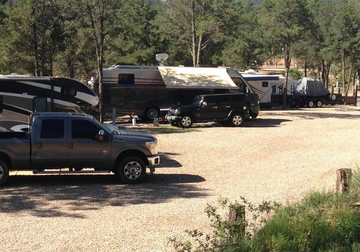 Gravel RV sites with parked rigs and tow vehicles under pine shade